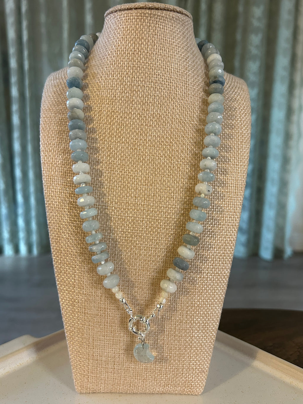Necklace with blue rondelle beads on a beige display stand