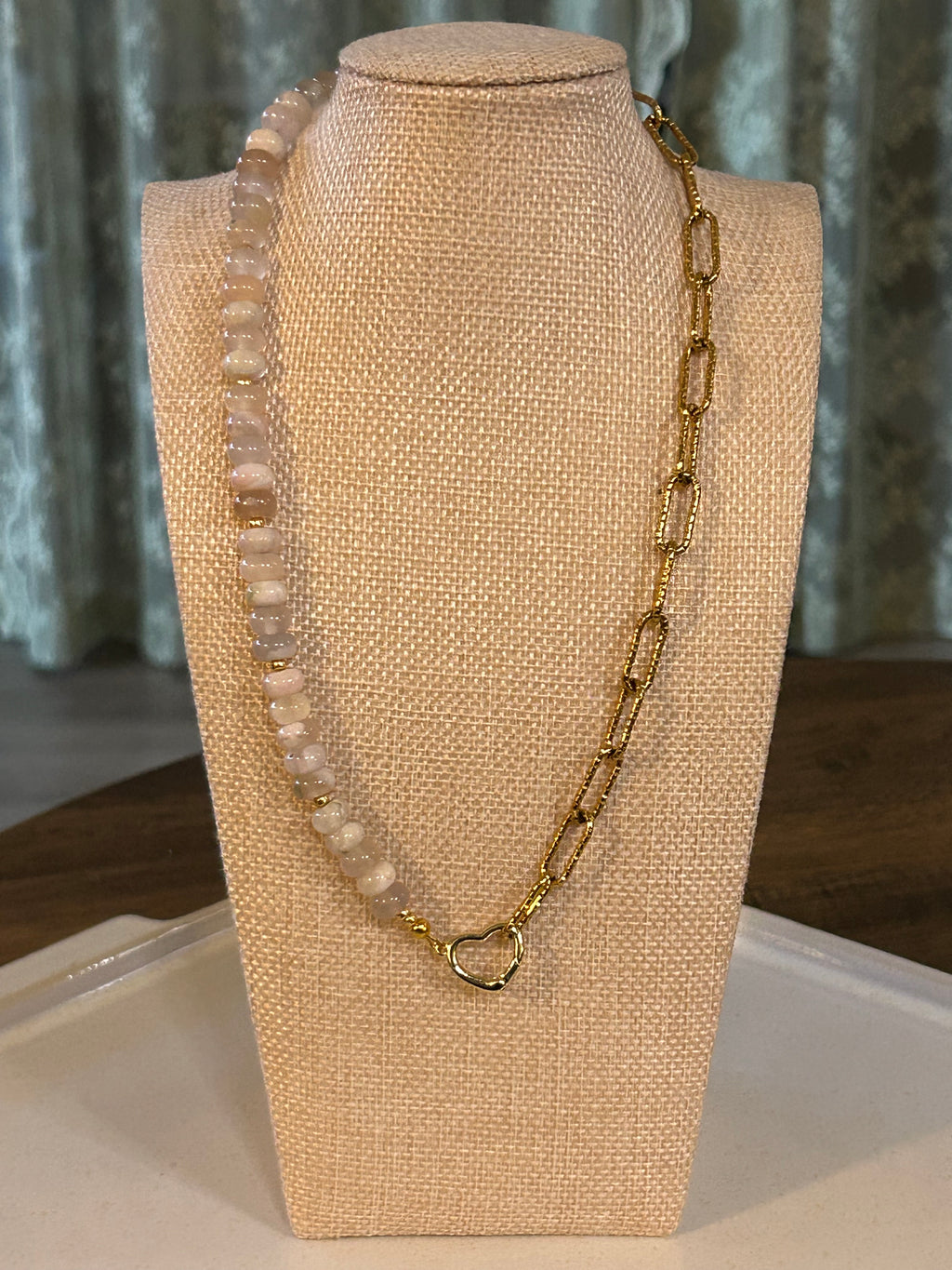 Gold necklace with beads on a beige jewelry display