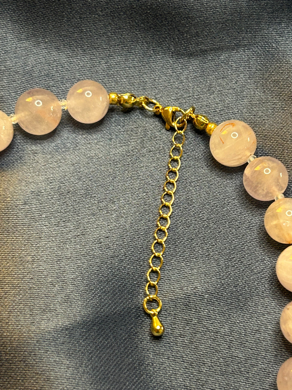 Necklace with purple beads and gold chain on a gray fabric background