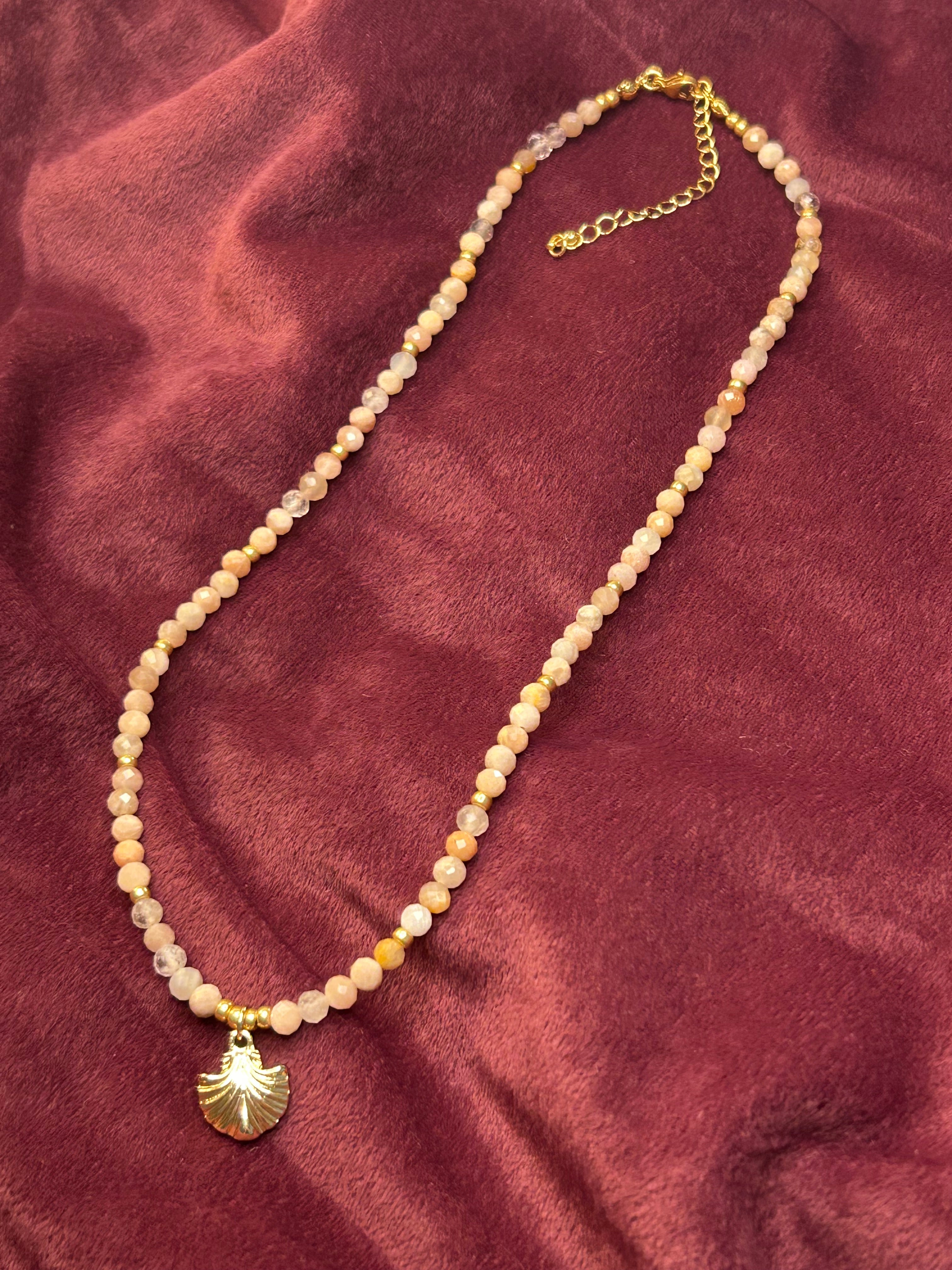 Necklace with gold chain and pendant on a maroon fabric background
