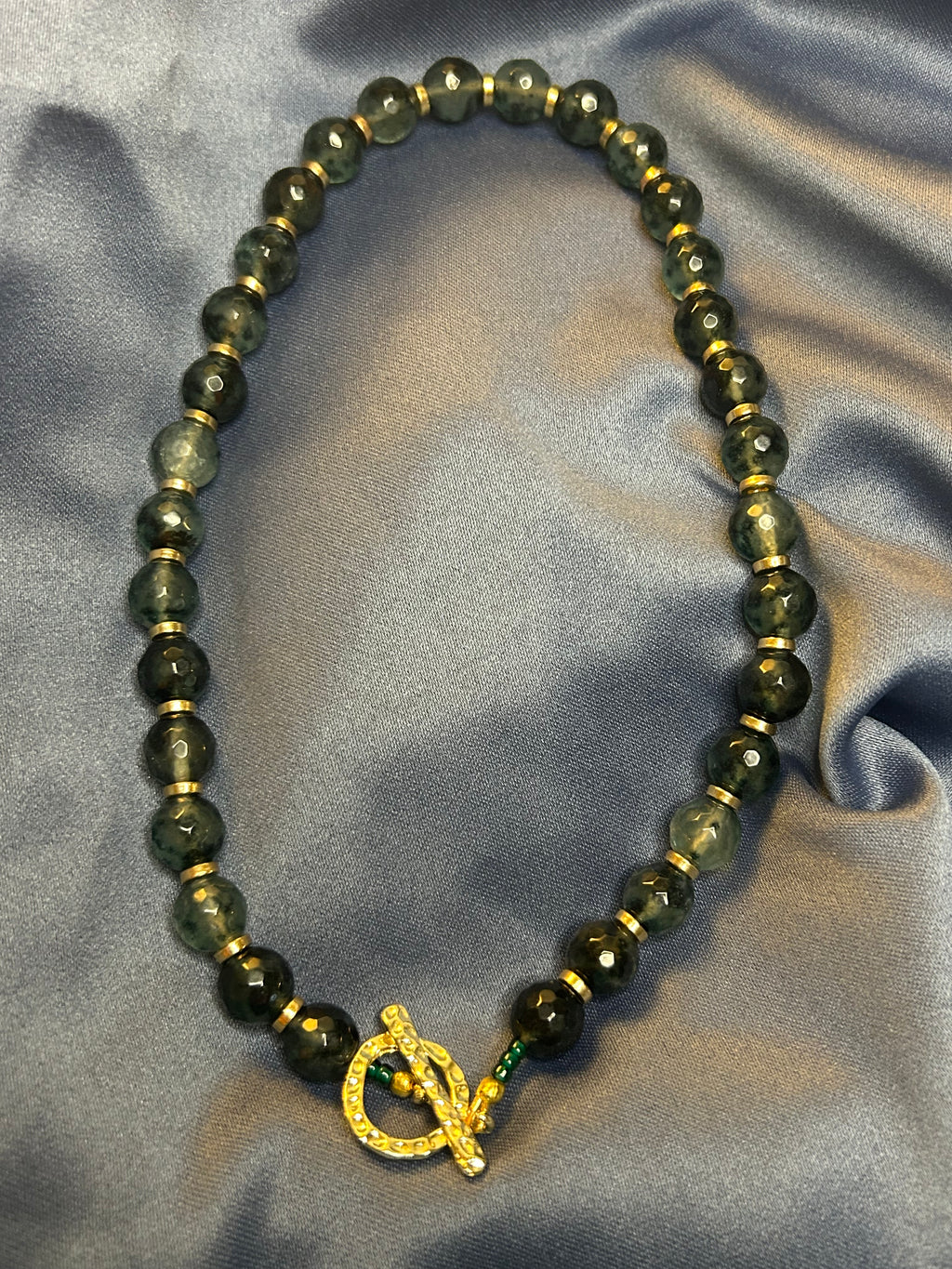 Beaded necklace with a gold clasp on a textured gray background