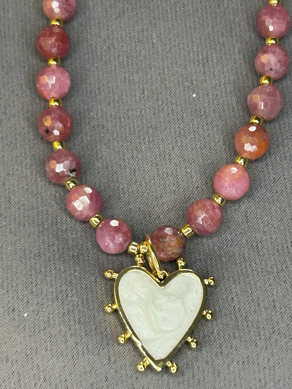 Necklace with pink beads and a heart-shaped pendant on a gray background
