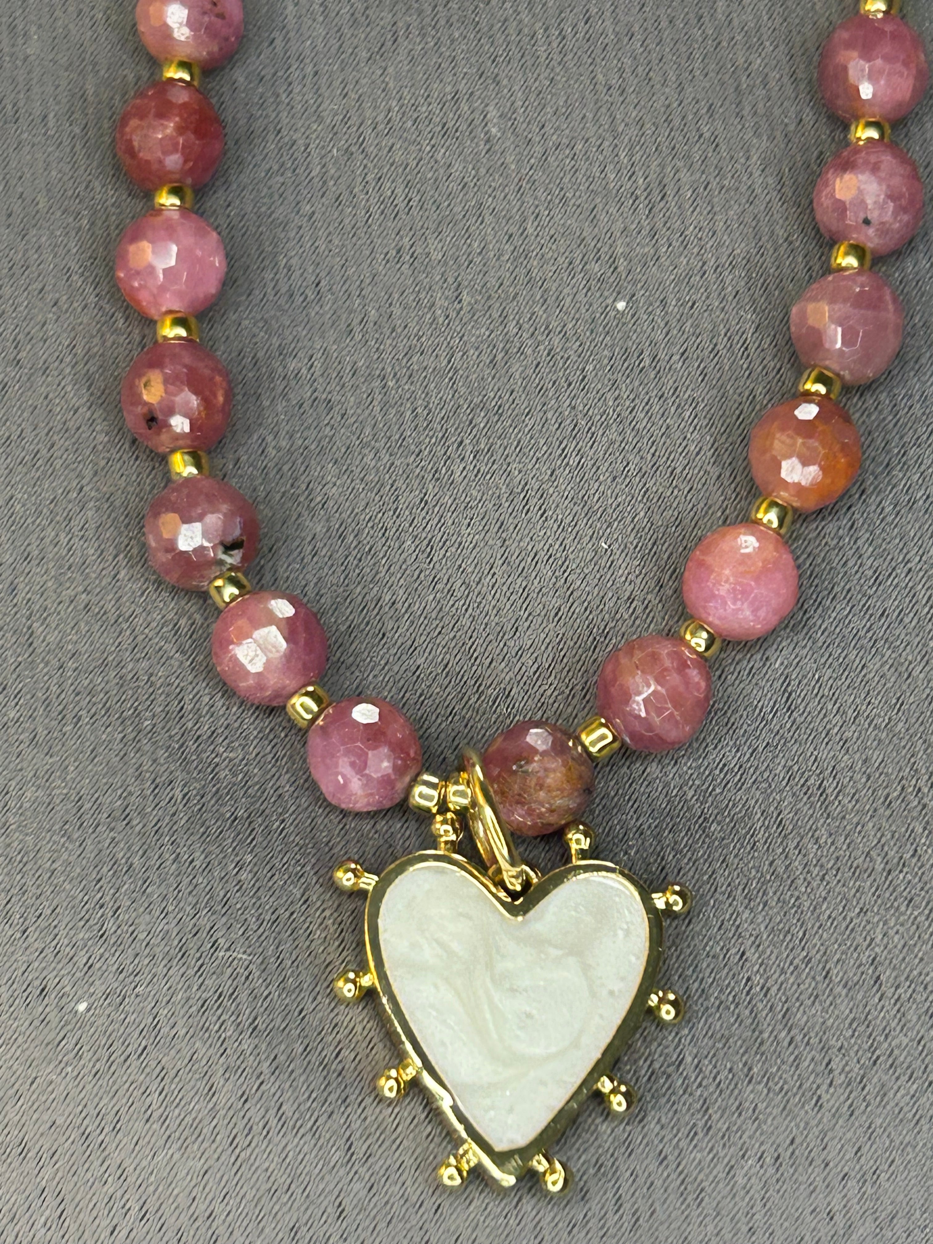 Necklace with pink beads and a heart-shaped pendant on a gray background