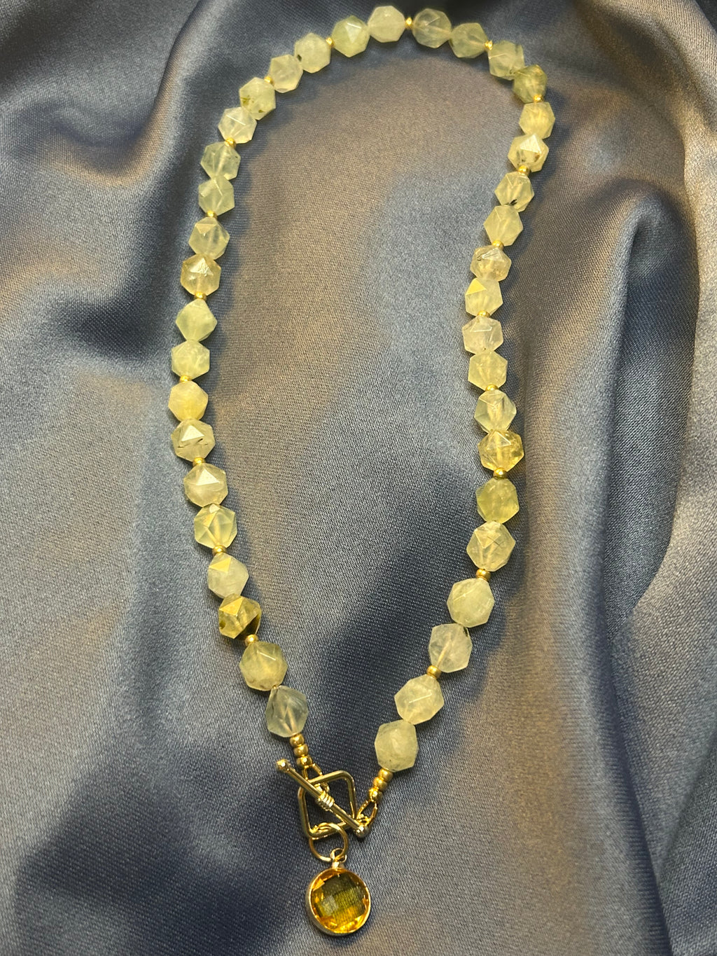 Necklace with green-yellow beads on a gray fabric background