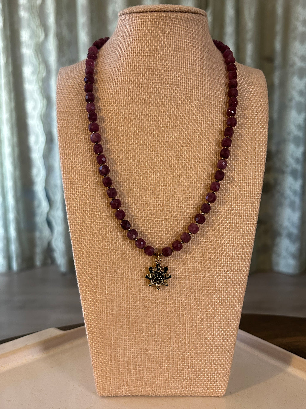 Beaded necklace with a flower-shaped pendant on a beige display