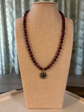 Beaded necklace with a flower-shaped pendant on a beige display