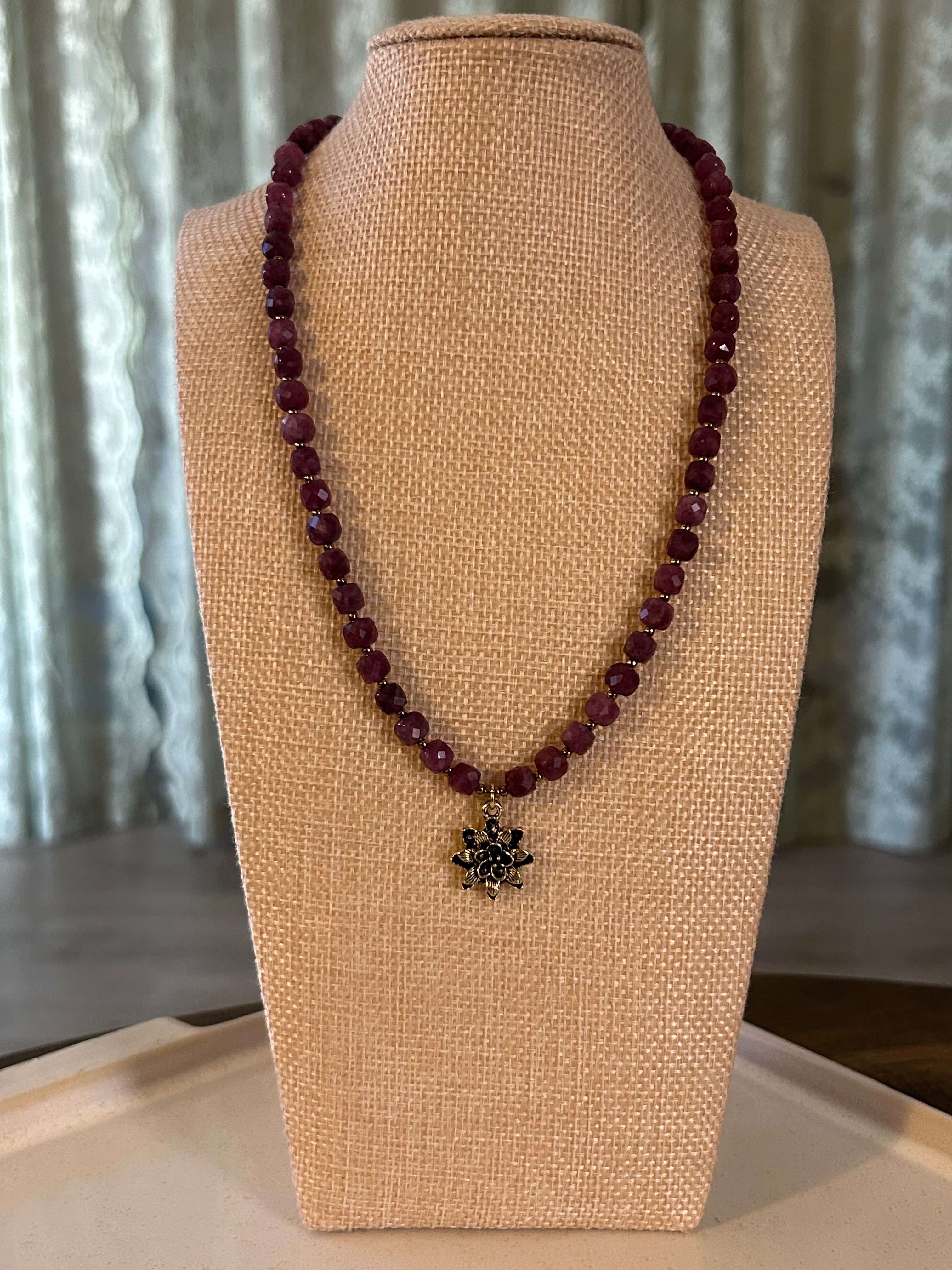 Beaded necklace with a flower-shaped pendant on a beige display